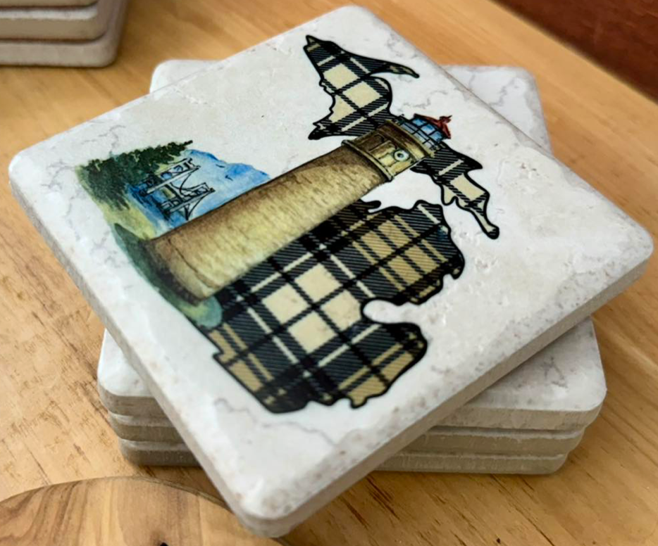 Stack of stone coasters with lighthouse design on a wooden surface